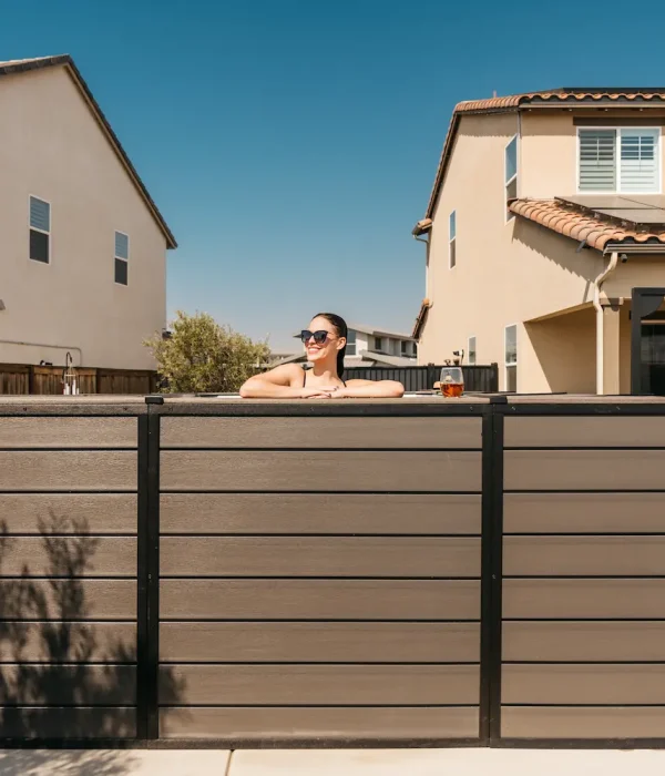 Woman relaxing in above-ground pool with sunglasses, surrounded by modern homes, showcasing family-friendly design and outdoor enjoyment.