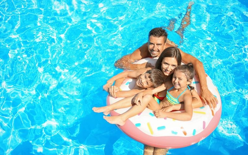 Happy family with inflatable ring relaxing in swimming pool